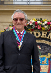 Director de la DNI con medallas frente a un arreglo floral y un escudo de Colombia.